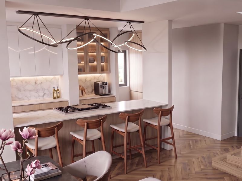 Modern kitchen featuring a marble-look island with integrated gas hob, custom cabinetry, and elegant herringbone timber flooring in a bright, open-plan layout.