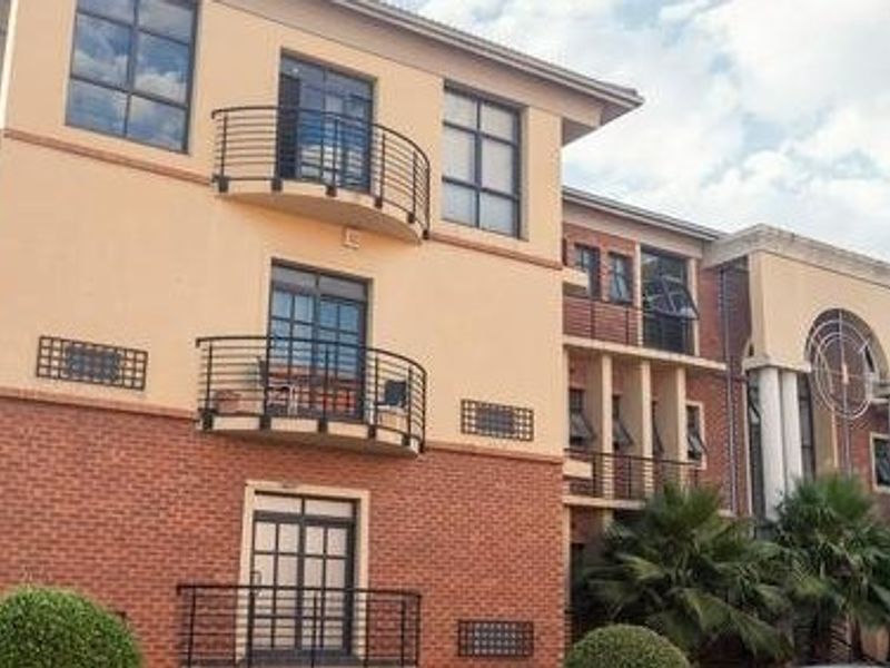 A multi-story commercial building featuring a combination of brick and plaster facade, external staircases, and multiple balconies with metal railings.