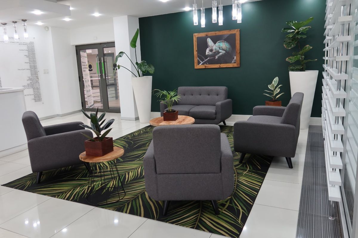 A modern commercial reception or waiting area featuring polished tiled floors, a dark green accent wall, and contemporary recessed lighting.
