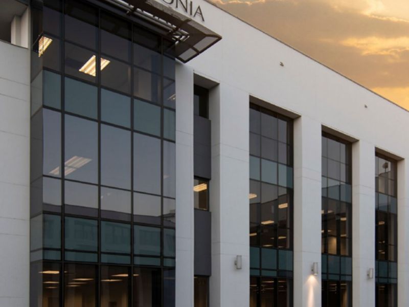 A modern commercial office building featuring extensive glass curtain walling, clean white facade finishes, and professional architectural design.