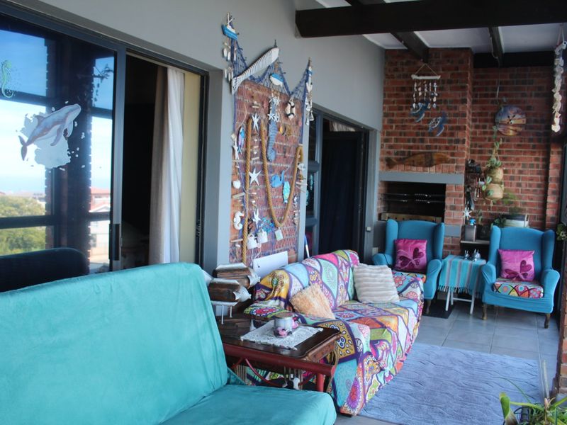 Covered patio area featuring exposed brick walls, a built-in braai, tiled flooring, and sliding glass doors leading to the interior.