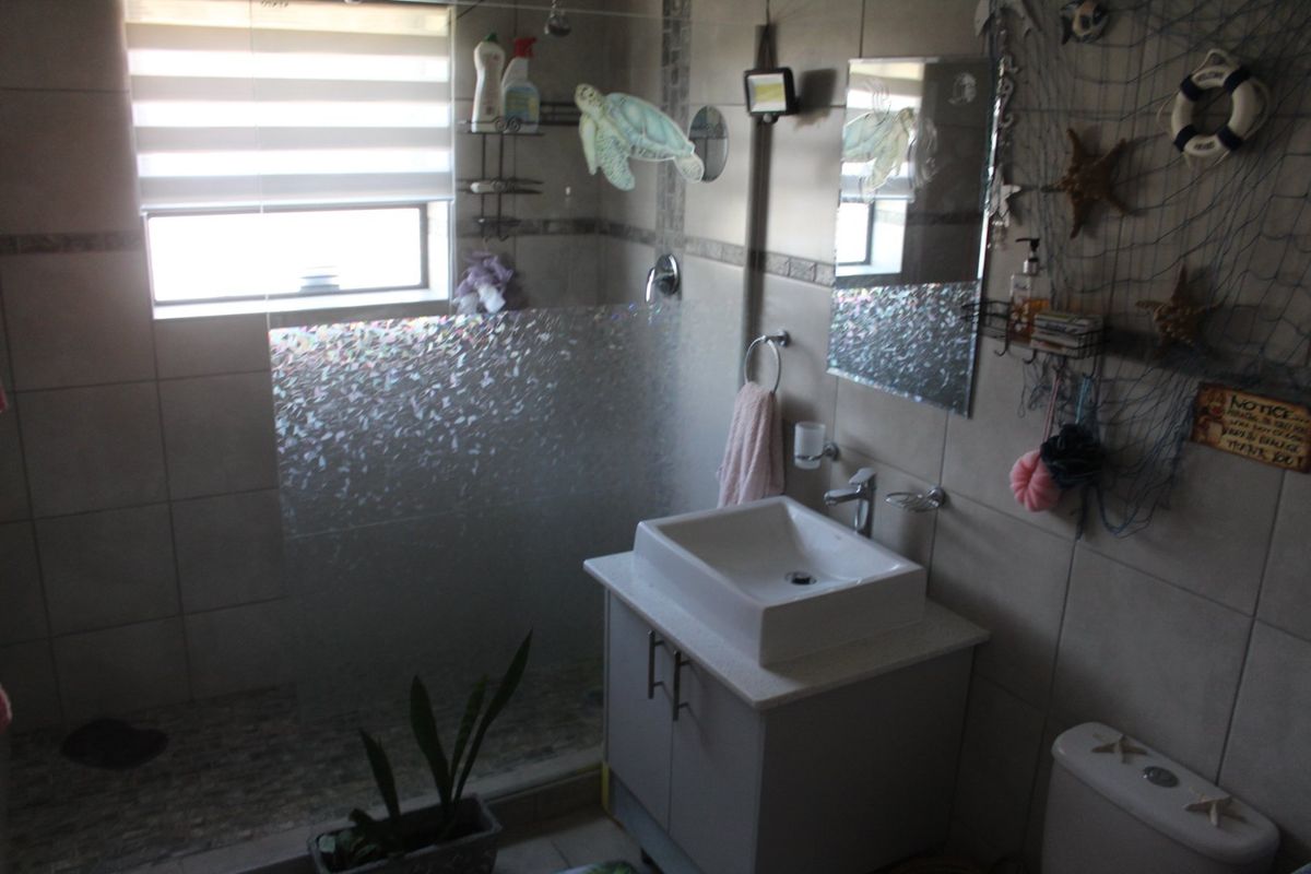 A functional bathroom featuring a vessel sink vanity, a walk-in shower with a glass screen, and neutral wall tiling.