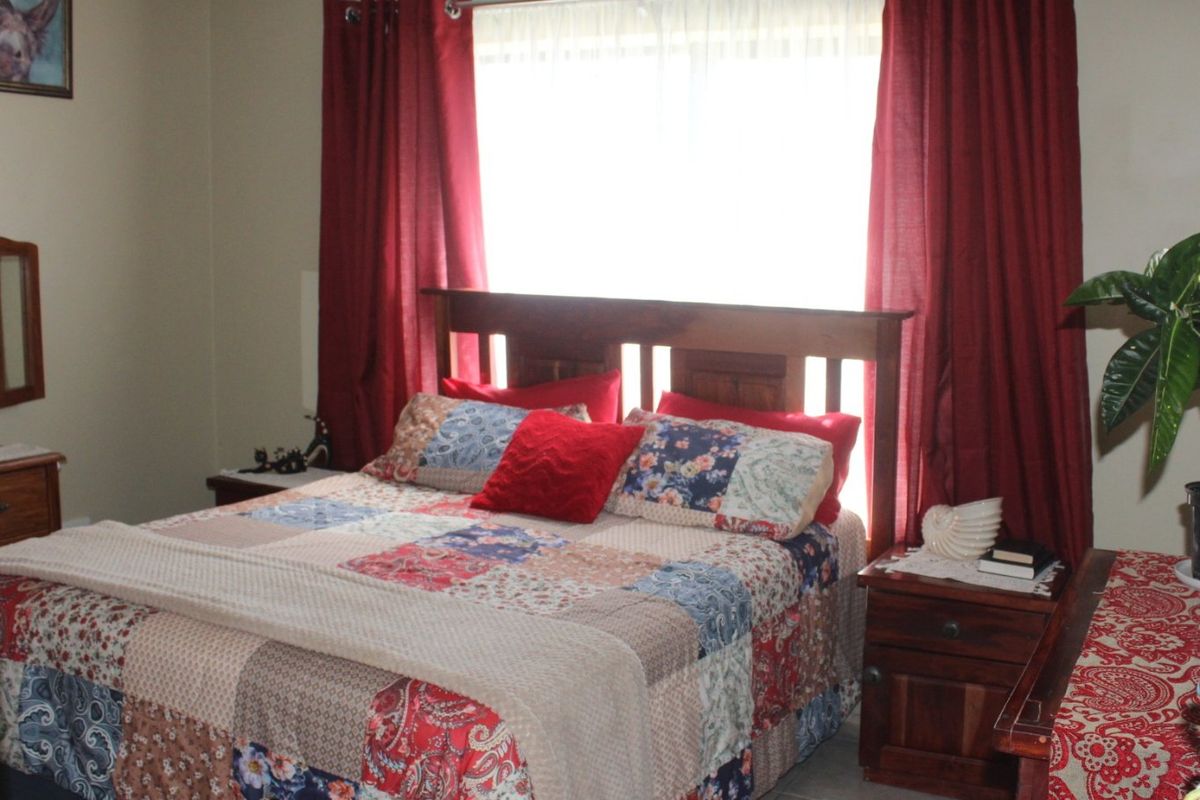 A bedroom featuring a window with red curtains and neutral wall finishes.