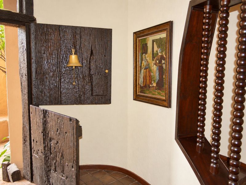 Entrance area featuring a rustic timber door, traditional wooden balustrade, and terracotta floor tiles.
