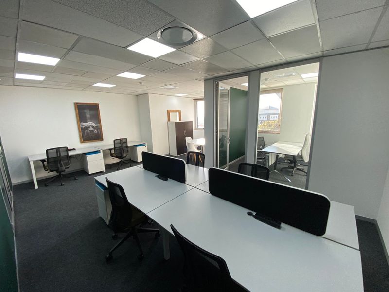 A modern commercial office space featuring glass partitions, suspended ceilings with recessed lighting, and carpeted flooring, providing a professional and functional work environment.