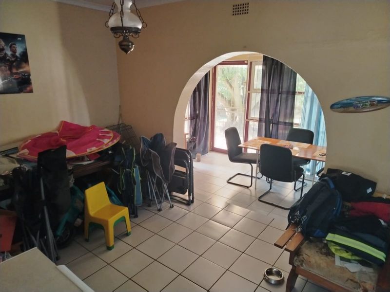 A living area featuring tiled flooring and a distinctive arched doorway leading to a patio area with sliding glass doors.
