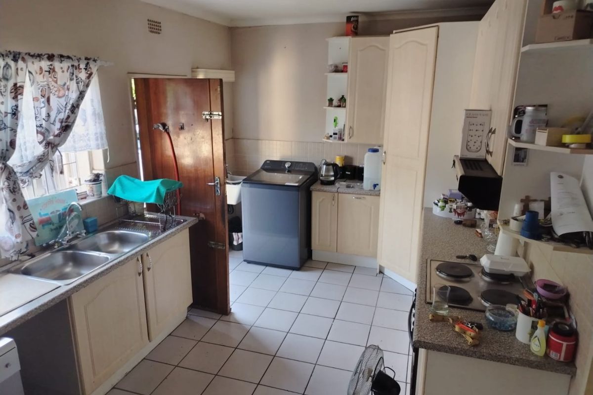 A functional kitchen featuring tiled flooring, laminate countertops, built-in cabinetry, and an electric hob, offering a practical layout for daily use.
