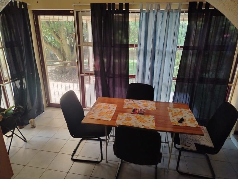 A dining area featuring tiled flooring and a sliding glass door with a security gate, providing direct access to the outdoor space.