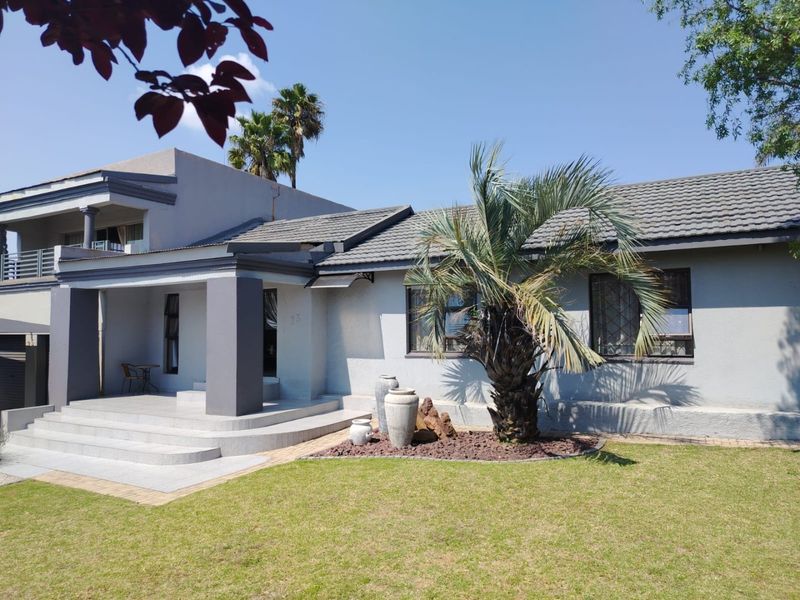 Front elevation of a well-maintained house featuring a covered porch, concrete steps, and a landscaped garden area.