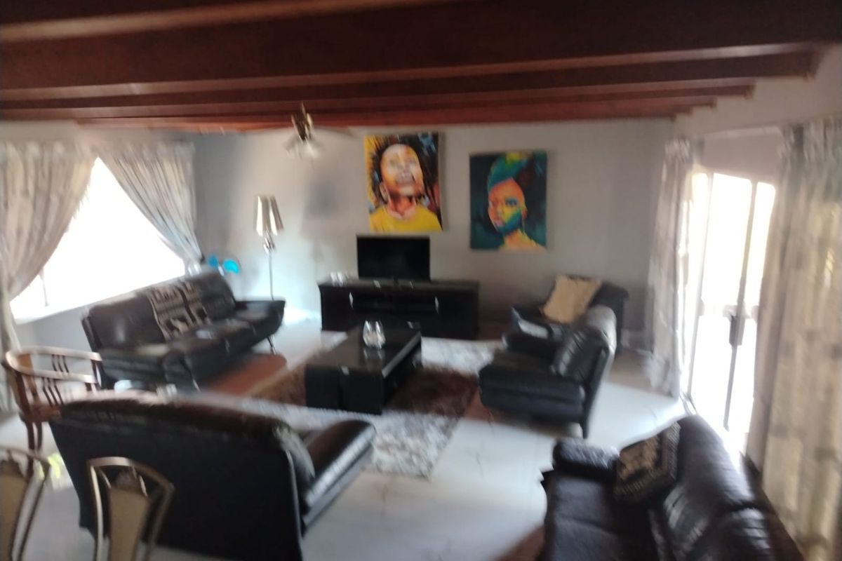 Spacious living room featuring exposed timber ceiling beams, tiled flooring, and large sliding glass doors providing natural light.