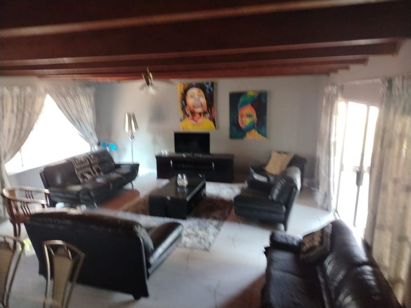 Spacious living room featuring exposed timber ceiling beams, tiled flooring, and large sliding glass doors providing natural light.