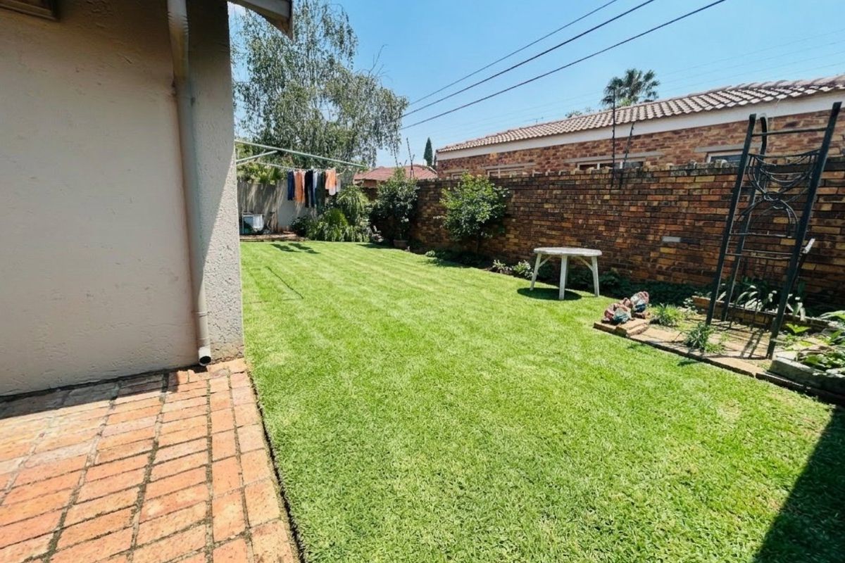 A private rear garden featuring a well-maintained lawn, brick paved patio area, and secure brick boundary walls.