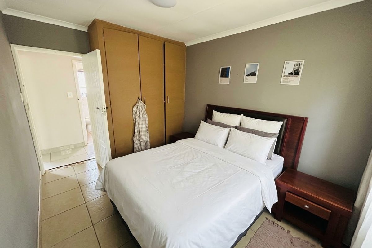 A functional bedroom featuring built-in cupboards, tiled flooring, and neutral wall tones, offering a clean and practical living space.