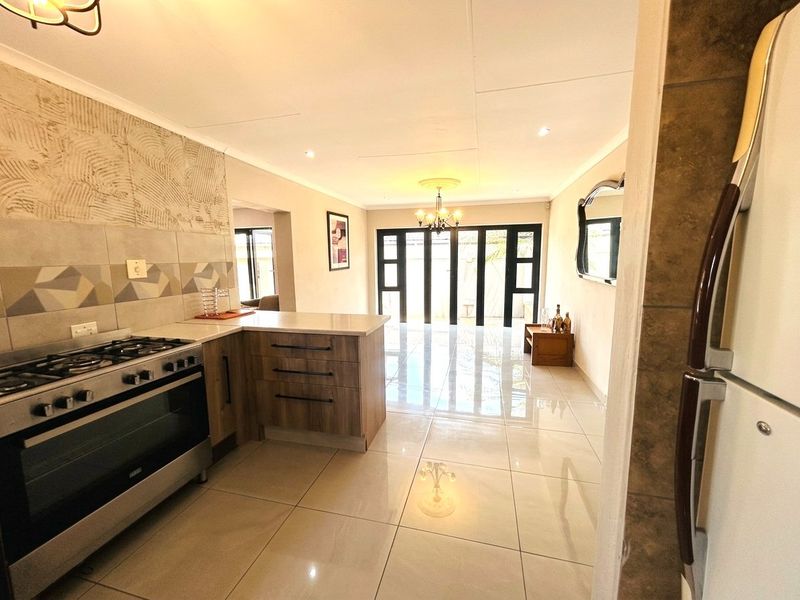 Open-plan kitchen and living area featuring modern cabinetry, gas stove, tiled flooring, and large sliding doors leading to the exterior.