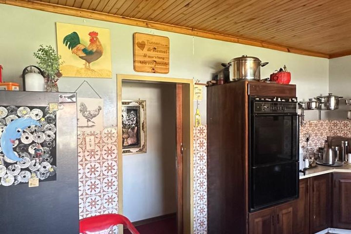 A dated kitchen featuring wooden ceiling paneling, tiled backsplash, and built-in oven cabinetry, offering potential for a modern renovation.