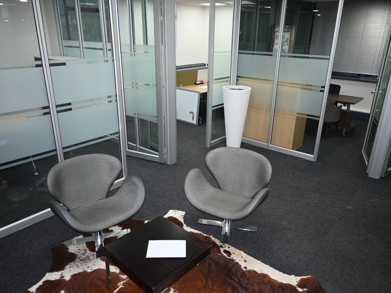Modern commercial office space featuring glass partition walls, aluminum framing, recessed lighting, and professional carpet flooring.
