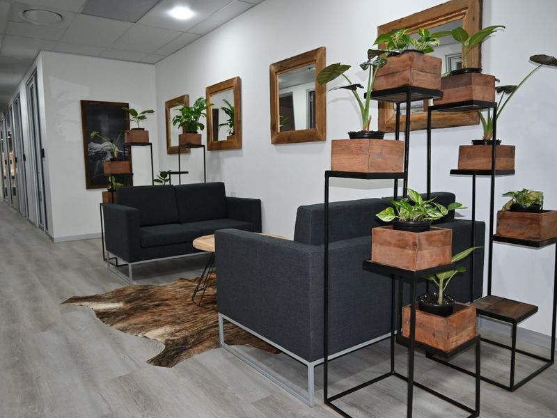 A modern commercial waiting area featuring laminate flooring, recessed ceiling lighting, and glass partition walls, creating a professional and bright atmosphere.