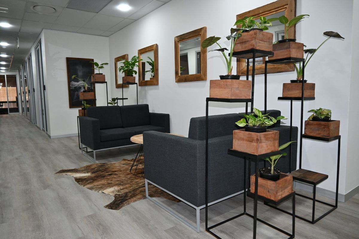 A modern commercial waiting area featuring laminate flooring, recessed ceiling lighting, and glass partition walls, creating a professional and bright atmosphere.
