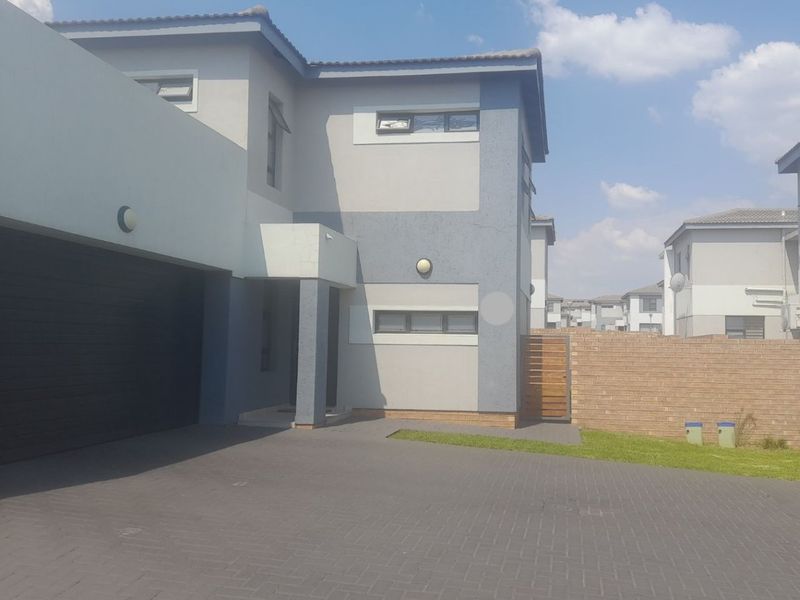 Modern double-story residential home featuring a paved driveway, integrated double garage, and a clean, contemporary facade with neutral exterior finishes.