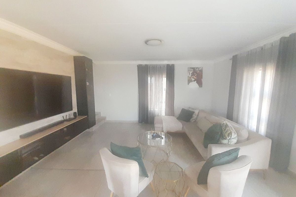 A spacious living room featuring tiled flooring, a built-in media console, and neutral wall finishes, offering a comfortable and functional living space.