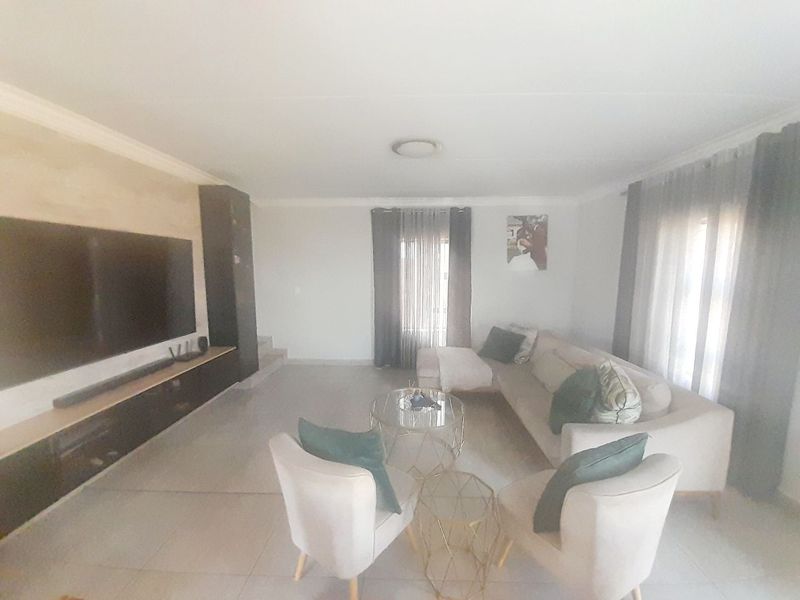 A spacious living room featuring tiled flooring, a built-in media console, and neutral wall finishes, offering a comfortable and functional living space.