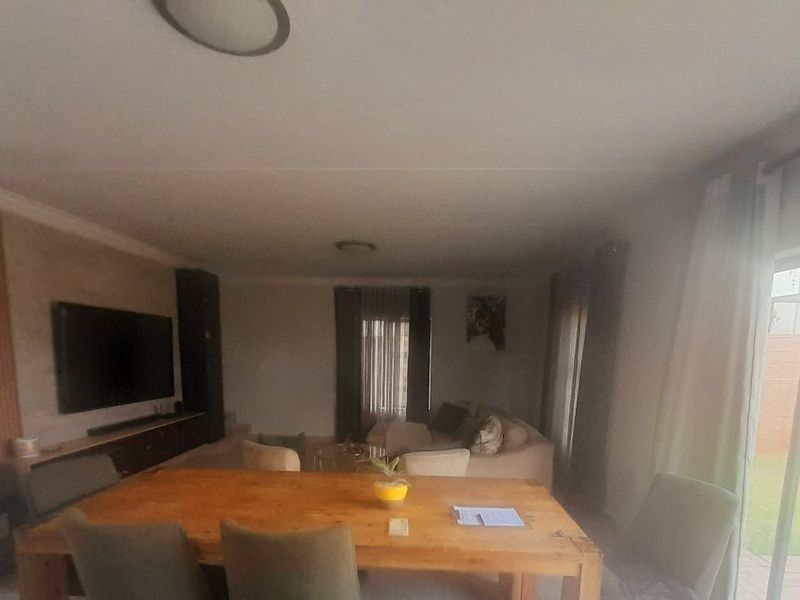 Open-plan living and dining area featuring slatted wood wall paneling, a built-in media unit, and direct access to the rear garden via sliding doors.
