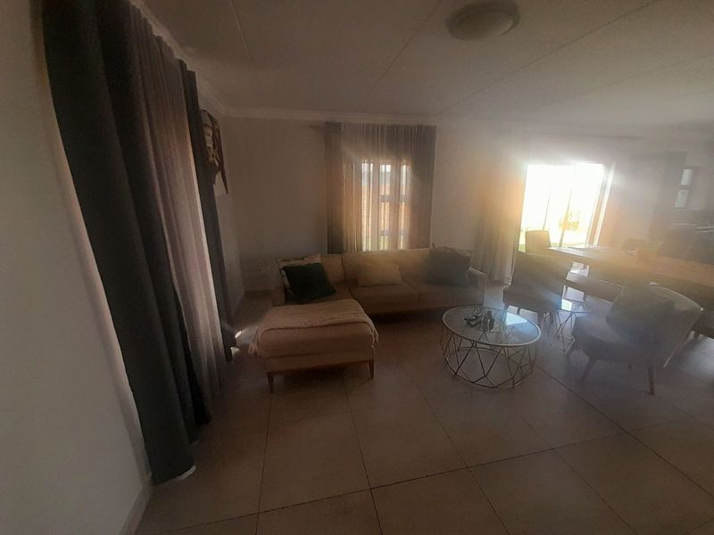 Open plan living and dining area featuring tiled flooring and large sliding glass doors providing natural light and garden access.