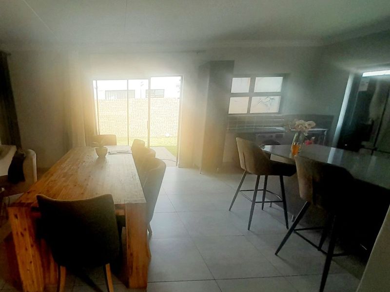 Open-plan living and dining area featuring tiled flooring, a kitchen island, and direct access to the rear garden through sliding glass doors.