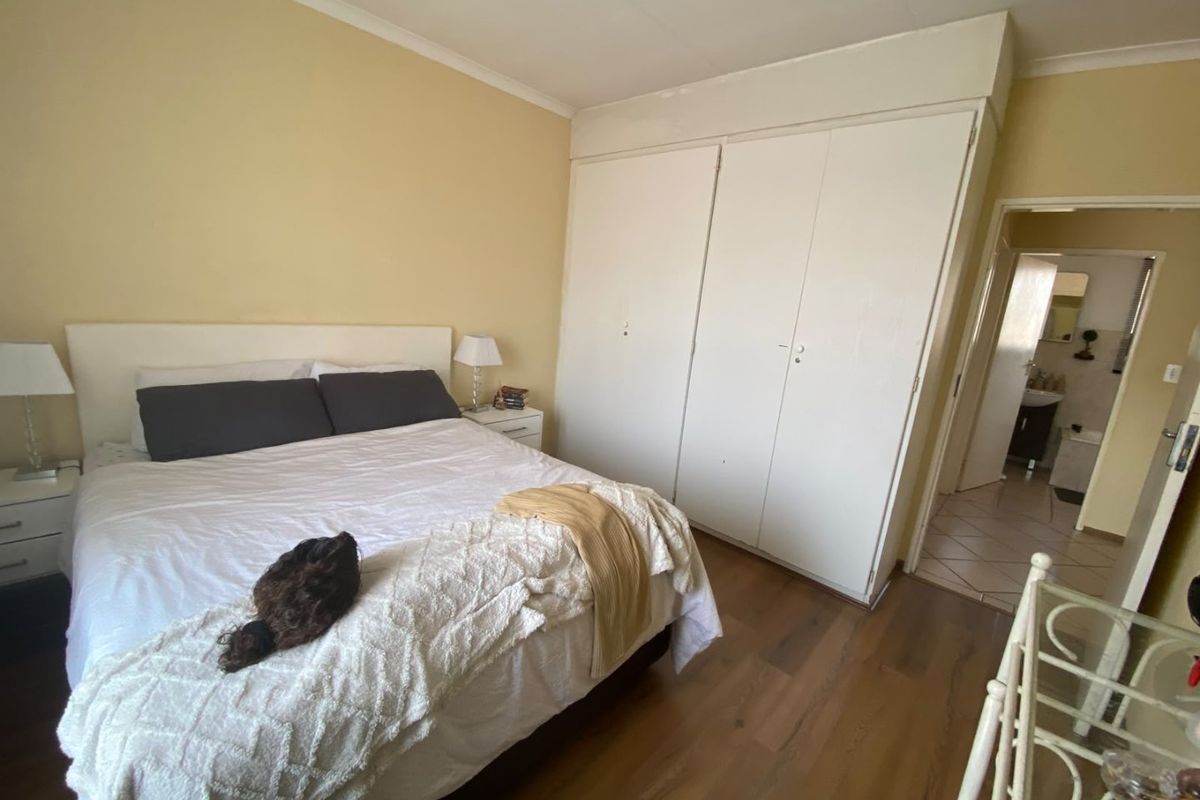 A bedroom featuring laminate flooring, built-in cupboards, and access to an adjoining bathroom.