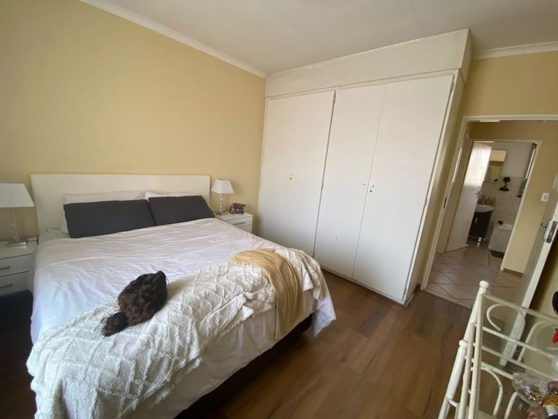 A bedroom featuring laminate flooring, built-in cupboards, and access to an adjoining bathroom.