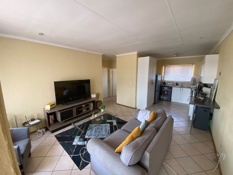 Open-plan living area featuring tiled flooring and an integrated kitchen space with built-in cabinetry and sink.