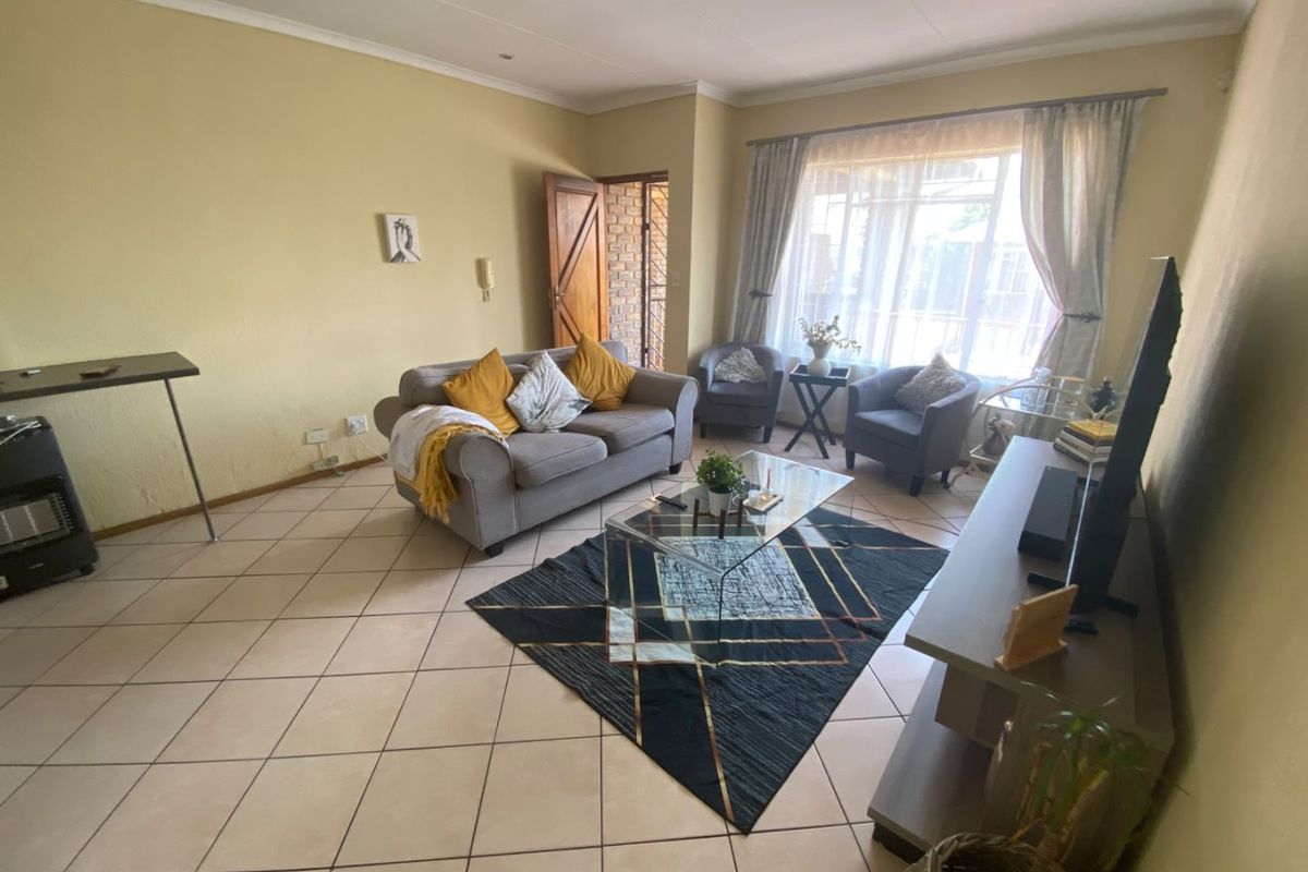 A spacious living room featuring tiled flooring, neutral wall tones, and large windows that provide ample natural light.