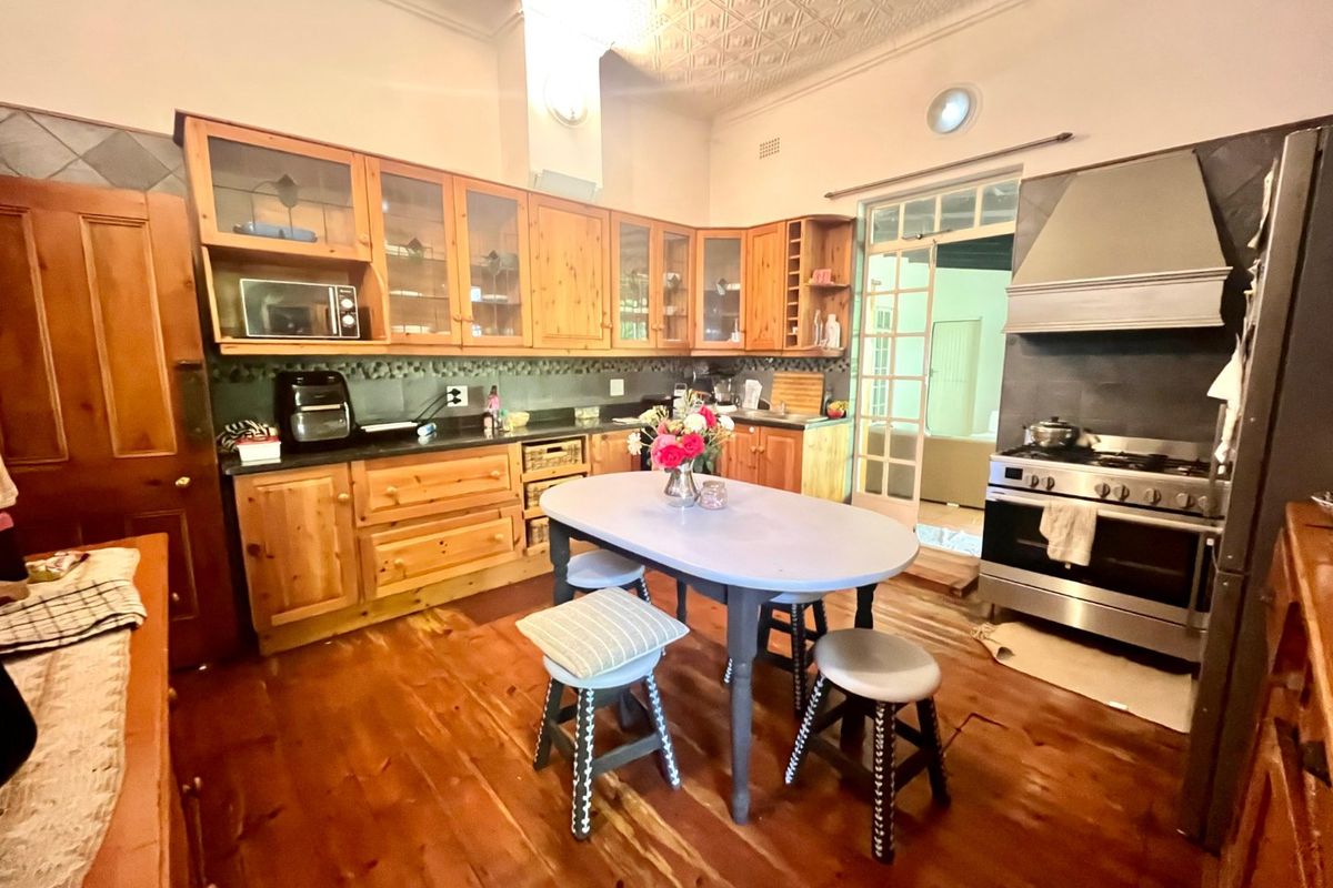 Spacious kitchen featuring timber cabinetry, a gas range cooker with stainless steel extractor, pressed metal ceilings, and original timber flooring.