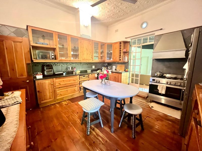 Spacious kitchen featuring timber cabinetry, a gas range cooker with stainless steel extractor, pressed metal ceilings, and original timber flooring.