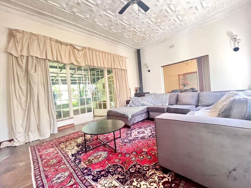 Spacious living room featuring a distinctive ornate pressed metal ceiling, ceiling fan, and large french doors providing access to the outdoor area.