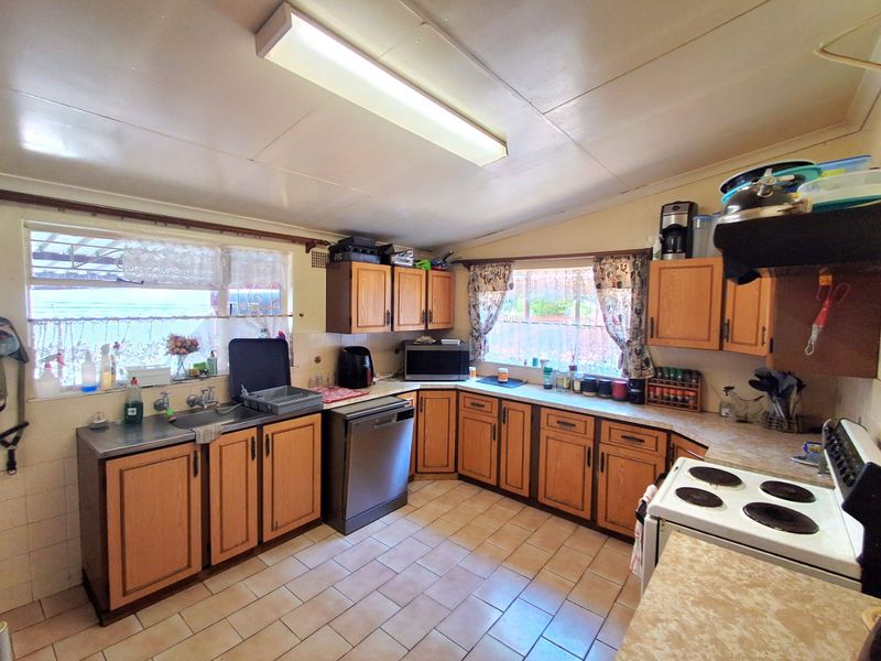 A functional kitchen featuring timber cabinetry, laminate countertops, tiled flooring, and a built-in electric stove, offering potential for modern updates.