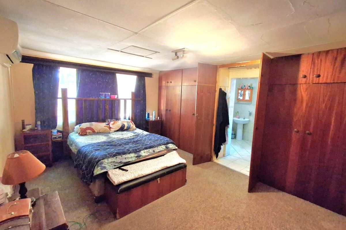 Spacious bedroom featuring extensive built-in wooden cabinetry, carpeted flooring, and direct access to an en-suite bathroom.
