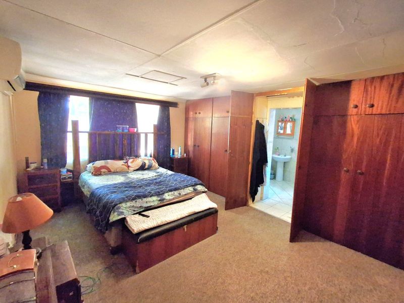Spacious bedroom featuring extensive built-in wooden cabinetry, carpeted flooring, and direct access to an en-suite bathroom.