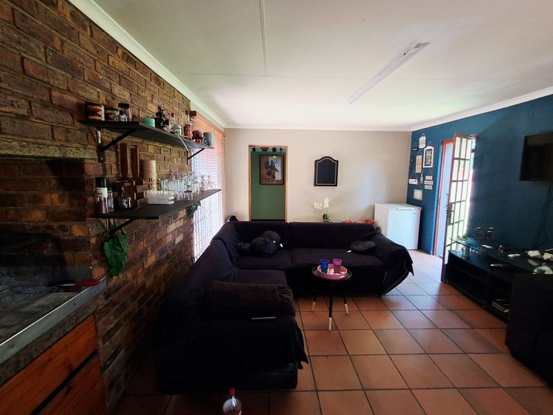 Living room featuring an exposed brick wall with a built-in fireplace and ceramic tile flooring, offering a rustic and functional living space.