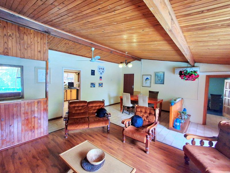 Spacious open-plan living and dining area featuring exposed timber ceiling beams, a mix of laminate and tiled flooring, and integrated air conditioning.