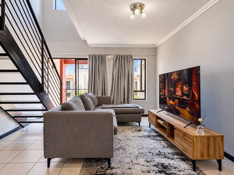 Spacious living room featuring tiled flooring, a modern staircase with metal balustrade, and large sliding glass doors leading to an outdoor area.