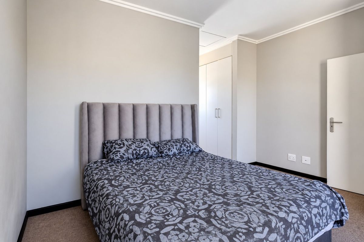 A well-maintained bedroom featuring neutral walls, carpeted flooring, coving, and built-in storage cupboards.