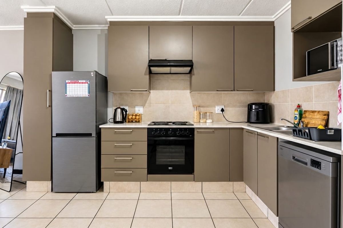 A functional kitchen featuring modern taupe cabinetry, tiled backsplash, built-in oven with hob, and tiled flooring.