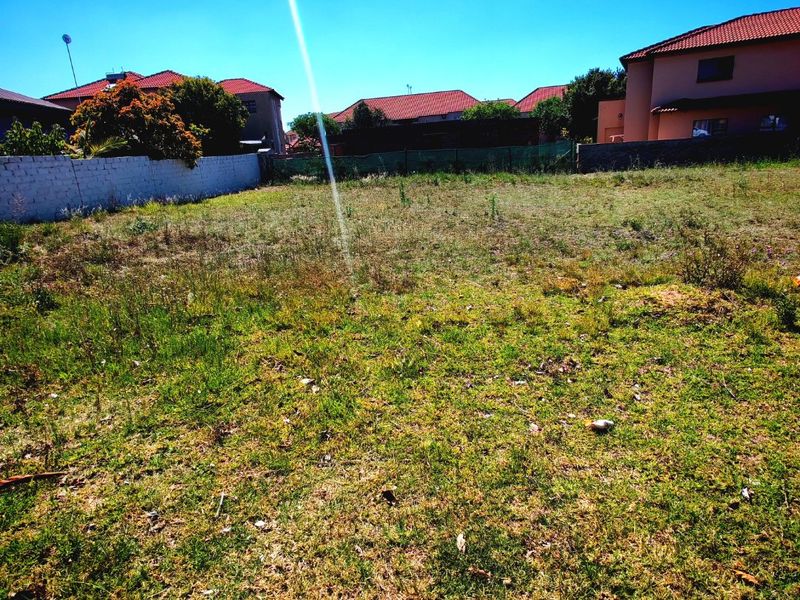 A vacant residential plot of land featuring perimeter walling and fencing, situated in a developed suburban neighborhood.