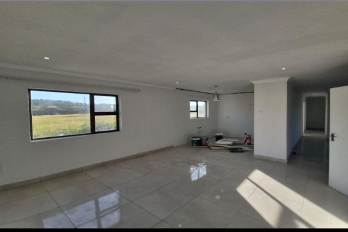 Spacious open-plan living area featuring large windows, tiled flooring, and recessed lighting, currently in an unfinished state awaiting final touches.