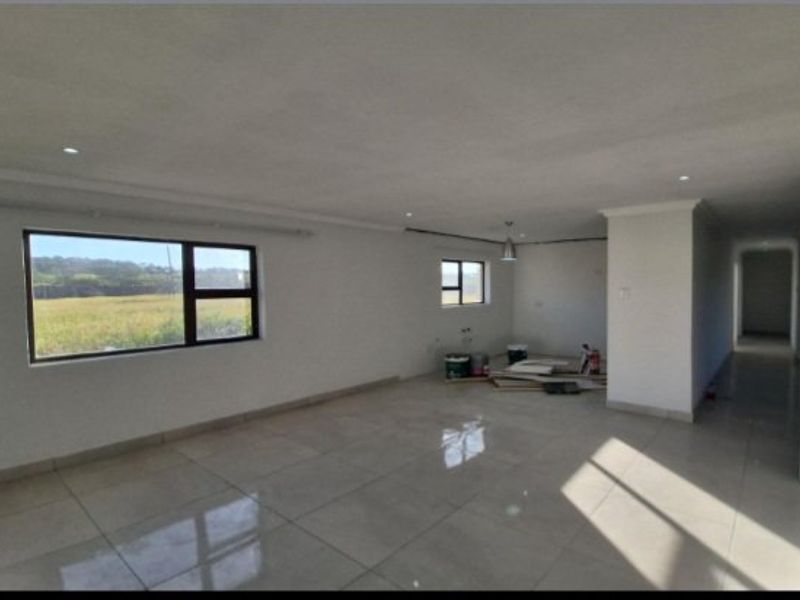 Spacious open-plan living area featuring large windows, tiled flooring, and recessed lighting, currently in an unfinished state awaiting final touches.