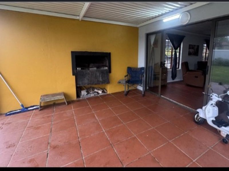 A covered patio area featuring a built-in braai, tiled flooring, and sliding glass doors providing access to the interior living space.