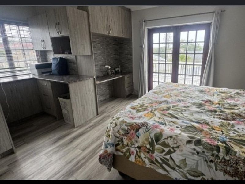 A bedroom featuring built-in cabinetry, laminate flooring, and french doors leading to an outdoor area.