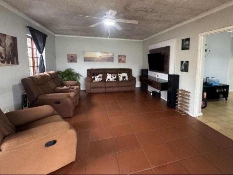 Spacious living room featuring tiled flooring, a ceiling fan, and a built-in media console, offering a comfortable and functional family living space.