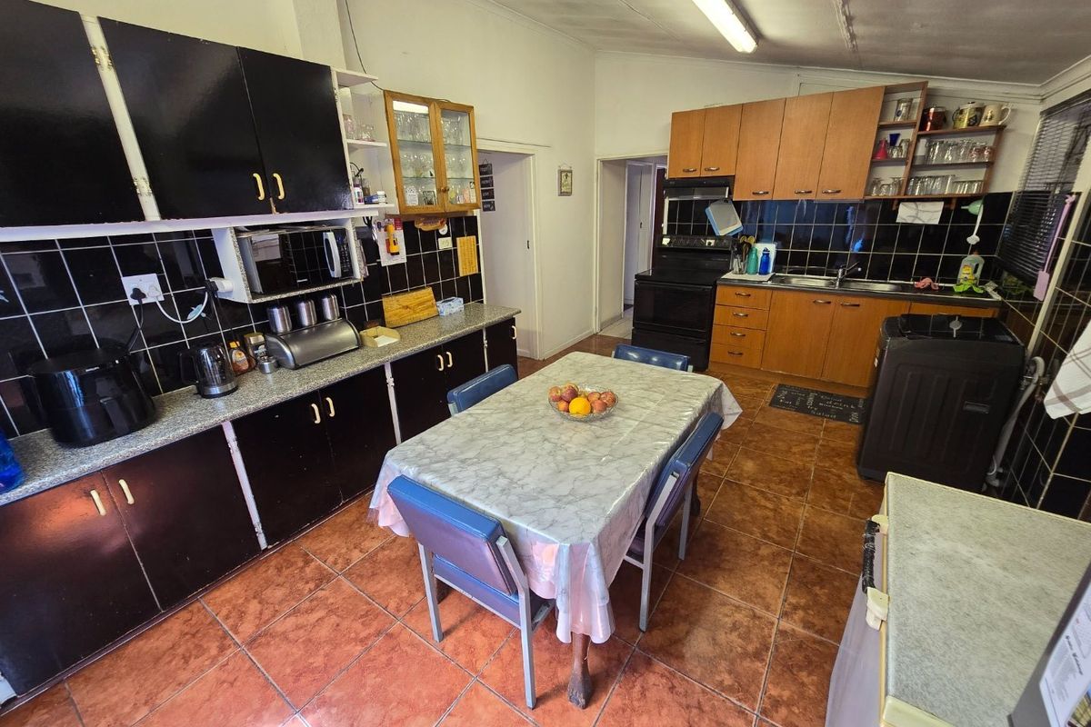 A functional kitchen featuring dark and wood-tone cabinetry, tiled backsplash, and ceramic flooring, offering a practical layout with integrated cooking and wash-up areas.
